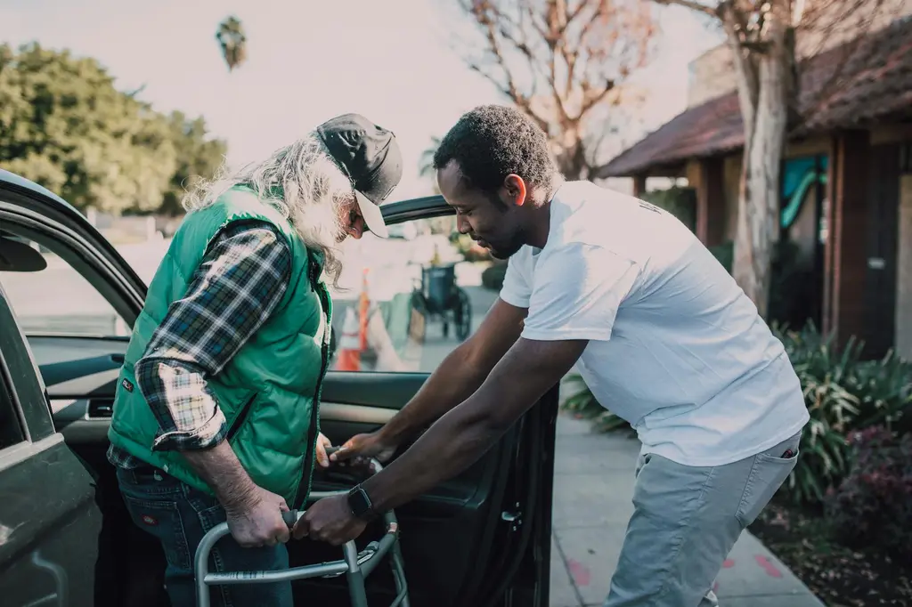 A volunteer helping a neighbor into a car